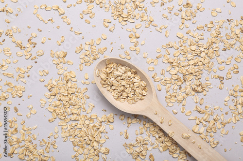 Wooden spoon with dry oatmeal on gray background