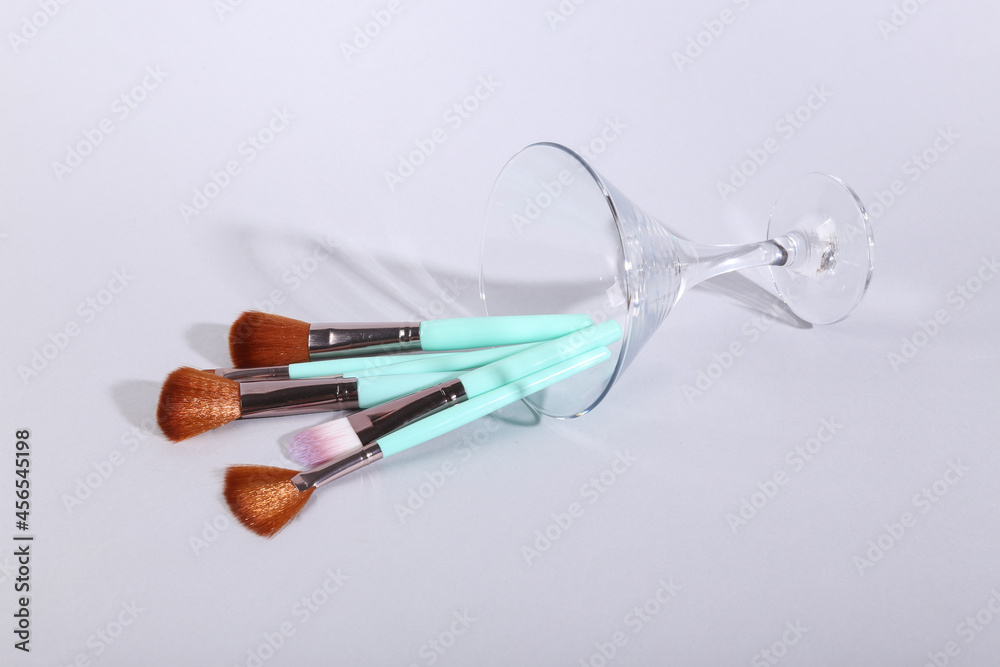 Makeup brushes in a cocktail glass on gray background. Minimal beauty layout Makeup brushes in a cocktail glass on gray background. Minimal beauty layout