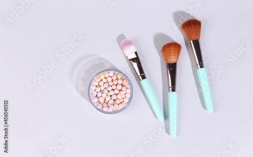 Powder balls in box with make-up brushes on gray background
