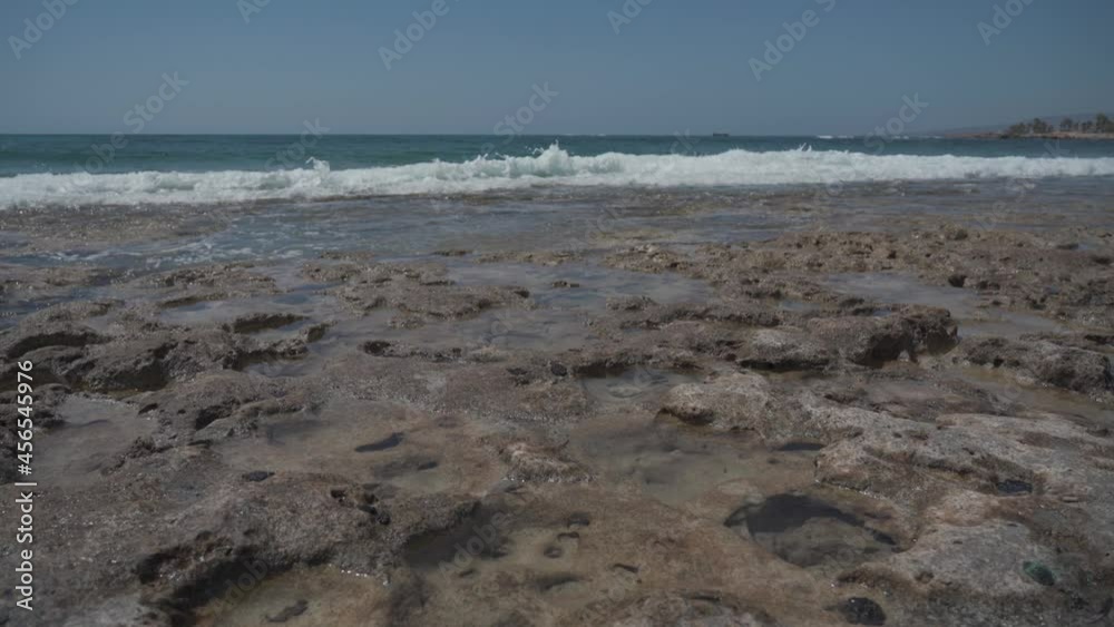 Waves of the Mediterranean Sea on a rocky coast in Cyprus near the city of Paphos in sunny summer weather. Crystal clear emerald water and rocky coastline of the Mediterranean Sea, Cyprus. Waves of the Mediterranean Sea on a rocky coast in Cyprus near the city of Paphos in sunny summer weather. Crystal clear emerald water and rocky coastline of the Mediterranean Sea, Cyprus.