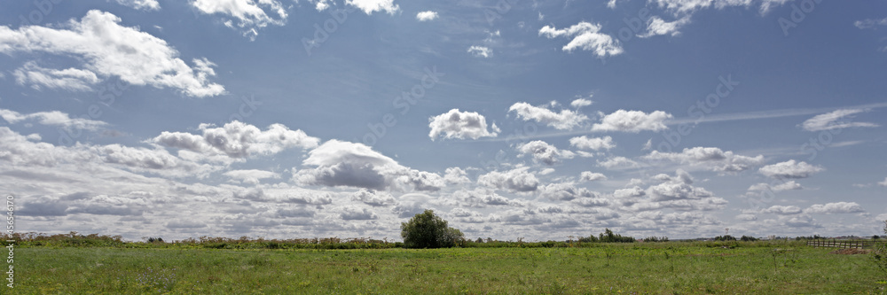 Blue sky with white fluffy clouds over green field