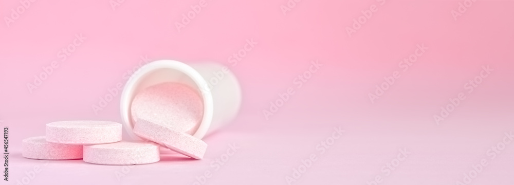 pink medicine tablets and glass bottle on pink background, top view, flat lay