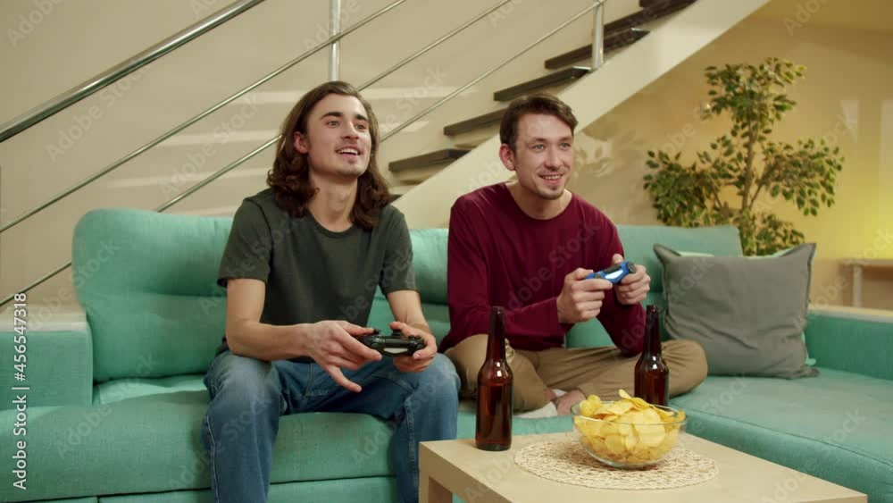 Two men are playing video games and laughing Two men are playing video games and laughing