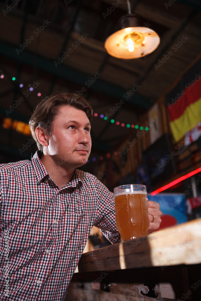 Vertical portrait of a man drinking beer at bar counter