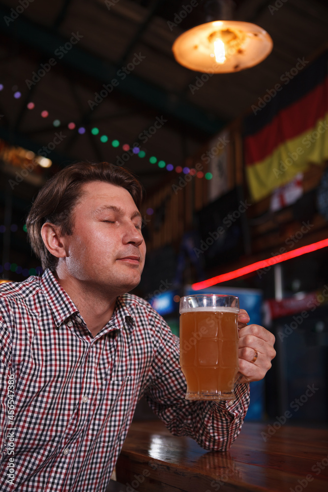 Vertical shot of a man enjoying craft beer at bar counter, smiling with eyes closed