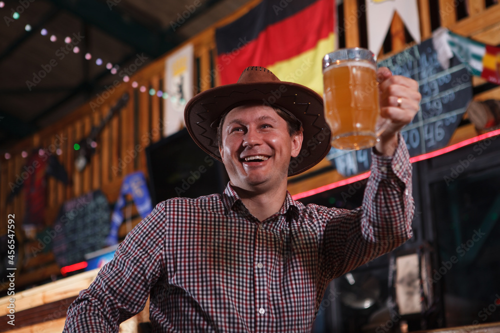 Low angle shot of a cheerful mature cowboy toasting with his beer glass at the bar