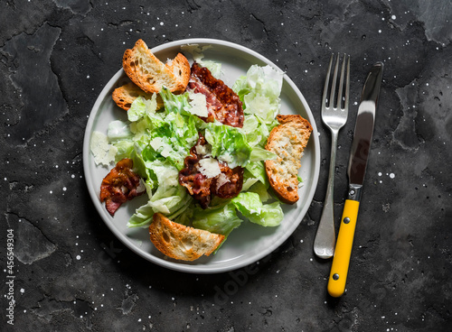 Caesar salad with bacon on a dark background, top view. Delicious brunch, appetizer, tapas