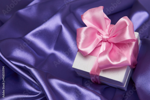 Christmas gift box with ribbon on silk background