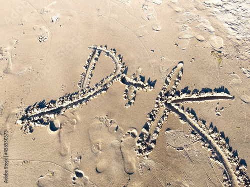 Top view of letters D and K of the alphabet written on the sand with upper case photo