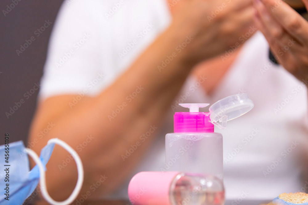 The close up photo of a cosmetic lotion in the pink bottle, spray and medical mask on the table to remove acne after appaired after using the face mask. The close up photo of a cosmetic lotion in the pink bottle, spray and medical mask on the table to remove acne after appaired after using the face mask.