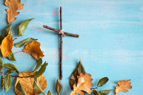 autumn leaf border with simple wood cross on blue wood background with copy space photo