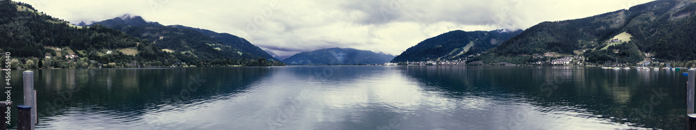 Zell am See. Zdjęcie panoramiczne na jezioro zrobione z pomostu. Wieczór z duża ilością chmur. Późne lato. W tle widać Alpy - Wysokie Taury. - obrazy, fototapety, plakaty 