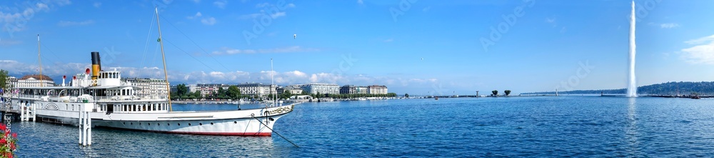 Panorama of Lake Geneva with the vintage white pleasure steamer and Jet Deau fountain near the pier in Geneva, Switzerland