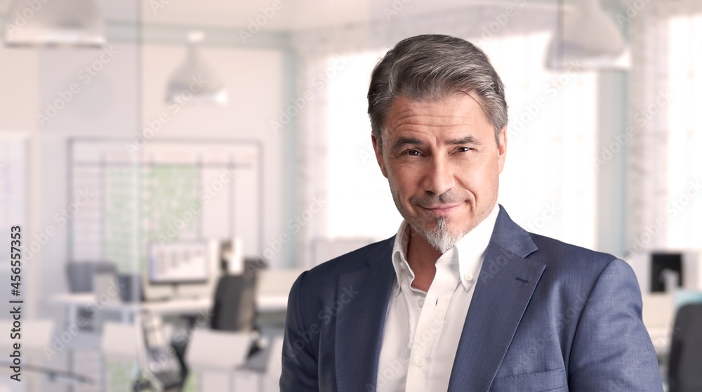 Confident businessman smiling in modern business office. Portrait of mature age, middle age, mid adult man in 50s, happy confident smile. Copy space. Confident businessman smiling in modern business office. Portrait of mature age, middle age, mid adult man in 50s, happy confident smile. Copy space.