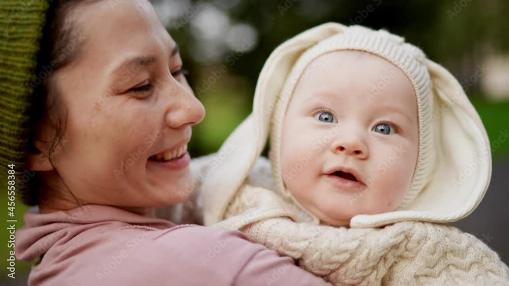 Cute baby in the mother's hands in summer nature. A joyful lifestyle of a happy mixed-race family. A young asian woman and active healthy baby with blue eyes in a rabbit costume. Childhood and Cute baby in the mother's hands in summer nature. A joyful lifestyle of a happy mixed-race family. A young asian woman and active healthy baby with blue eyes in a rabbit costume. Childhood and