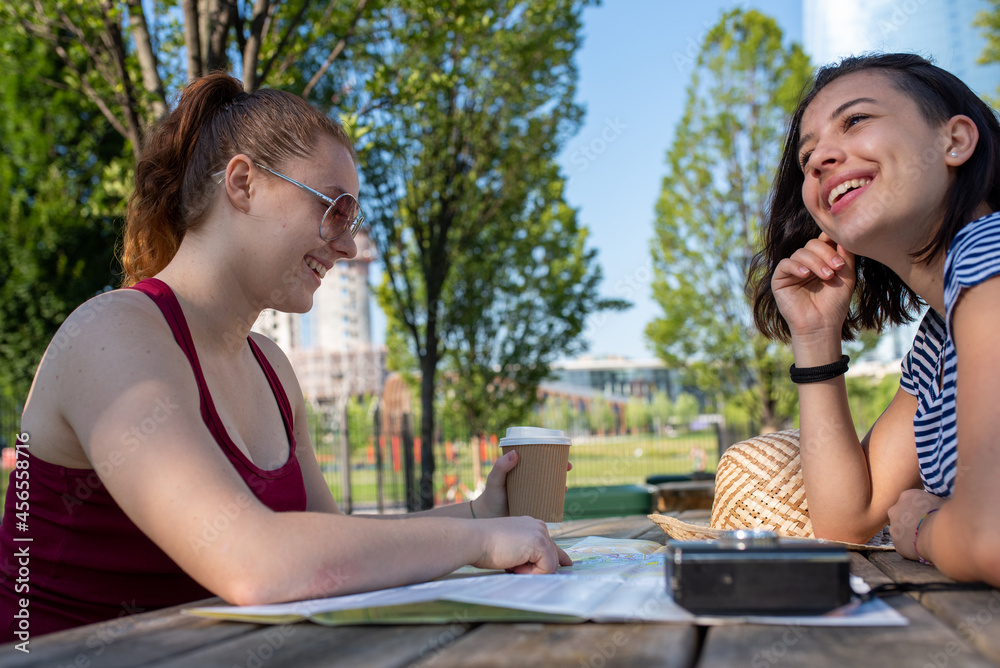 two young women tourists consult the map of the city to visit, young couple of girls on vacation two young women tourists consult the map of the city to visit, young couple of girls on vacation