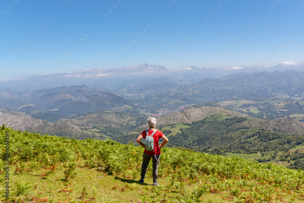 senior woman hiker contemplates the landscape from the top of a mountain