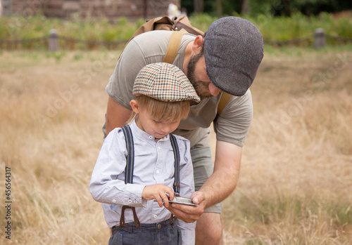 a boy with a dad in vintage clothes holds an old compass in his hands.