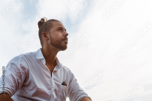 Portret mężczyzny ubranego w białą koszulę patrzący w niebo.