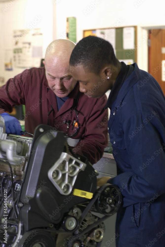 Teacher helping student with car engine