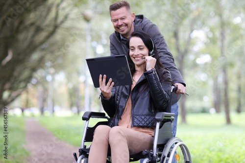 Disabled woman in wheelchair and man talking on digital tablet in park © megaflopp