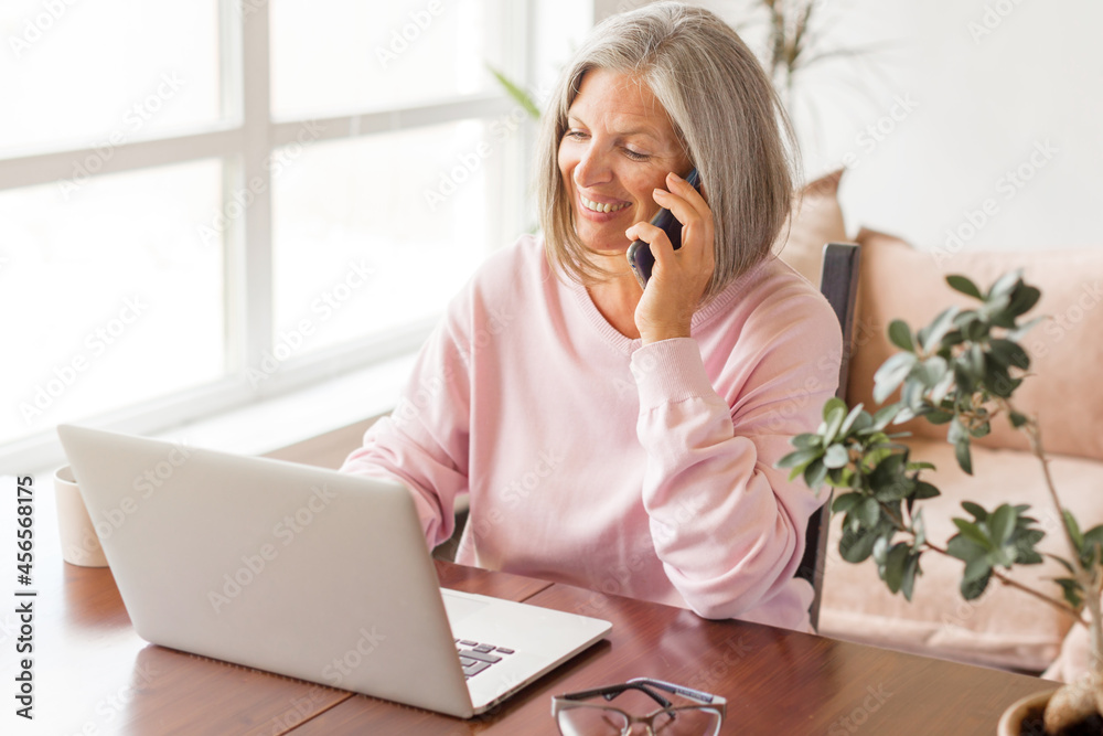 Happy stylish mature old woman remote working from home distance office on laptop Happy stylish mature old woman remote working from home distance office on laptop