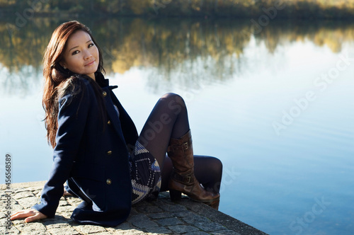 Quadro su tela Woman sitting by still lake