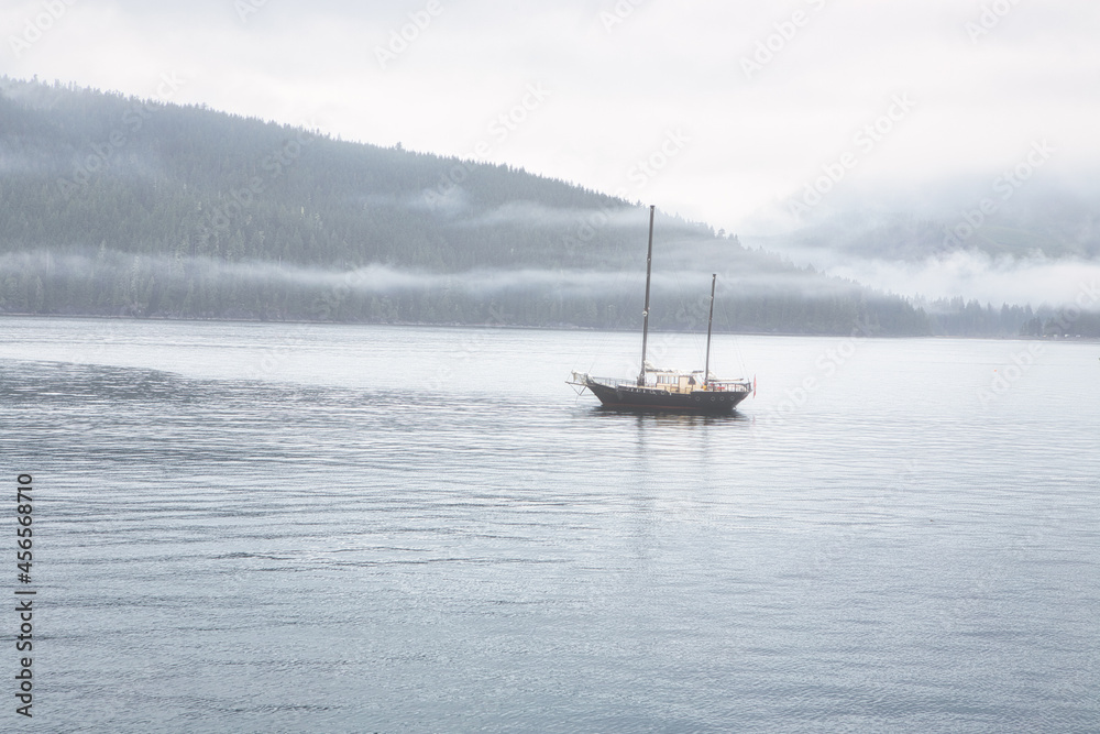 Sailboat parked in the ocean near Port Renfrew during a cloudy summer day. Located in Vancouver Island, British Columbia, Canada.