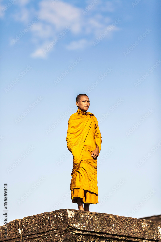 Fototapeta premium Young Buddhist monk standing outside temple in Angkor Wat, Siem Reap, Cambodia