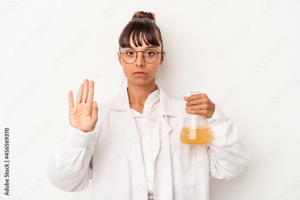 Young mixed race scientist woman holding a test tube isolated on white background standing with outstretched hand showing stop sign, preventing you. Young mixed race scientist woman holding a test tube isolated on white background standing with outstretched hand showing stop sign, preventing you.