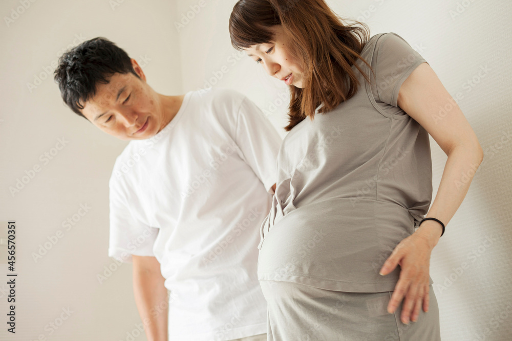 Man and pregnant woman looking down at stomach, portrait Man and pregnant woman looking down at stomach, portrait