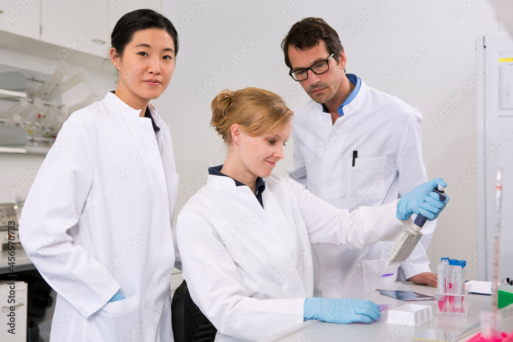 Group of scientists testing in laboratory, pipetting solution Group of scientists testing in laboratory, pipetting solution