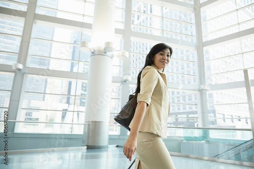 Businesswoman pulling wheeled suitcase through Staten Island Ferry terminal