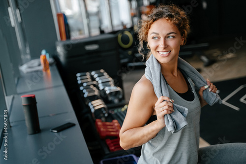 Happy woman after an intense workout in the gym is resting with towel. Concept of fitness and a healthy lifestyle