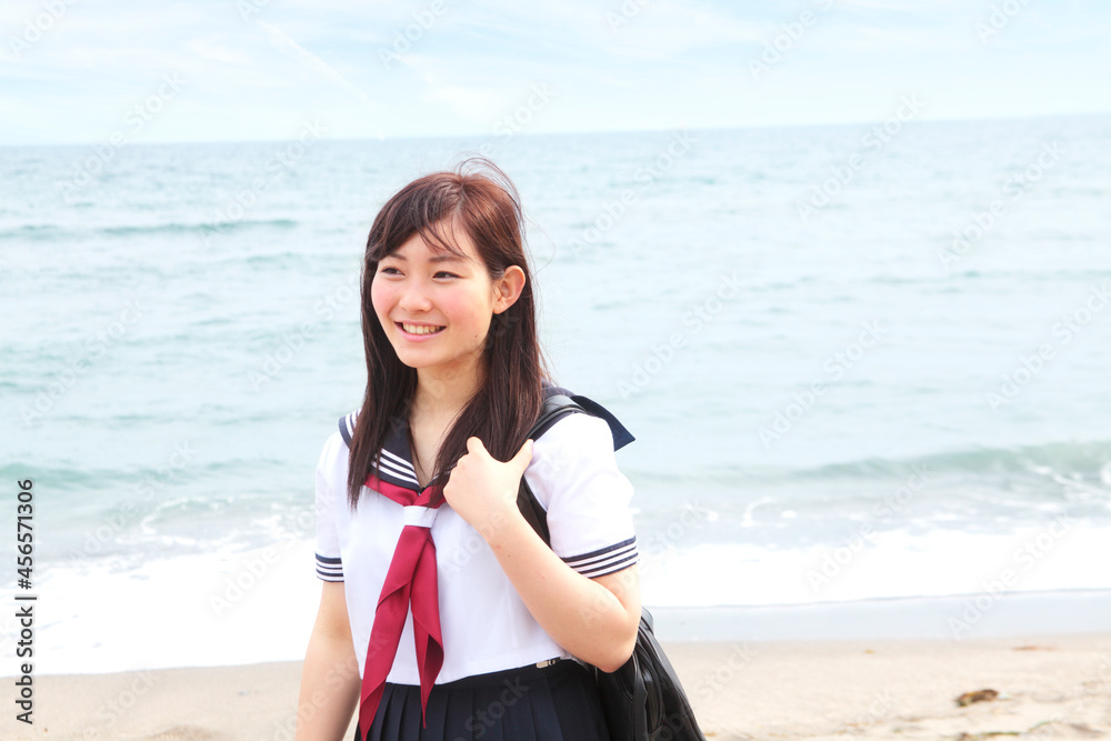 Young woman standing on beach wearing school uniform Young woman standing on beach wearing school uniform