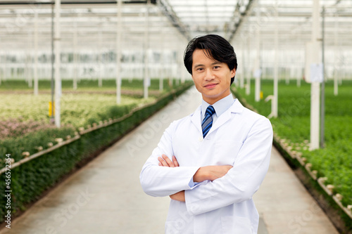 Foto Scientist standing in front of rows of plants growing in greenhouse, arms folded