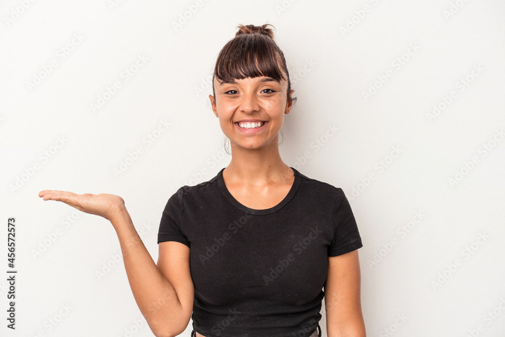 Young mixed race woman isolated on white background showing a copy space on a palm and holding another hand on waist. Young mixed race woman isolated on white background showing a copy space on a palm and holding another hand on waist.