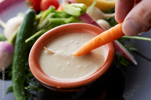 Quadro em tela Close up of young woman's hand dipping carrot into sauce