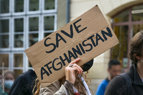 Female activist holding a cardboard sign with text Safe Afghanistan at a demonstration in Lubeck, Germany after the Taliban takeover