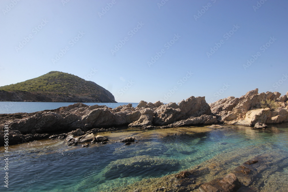 Rocks and rocky landscape visible in clear water.