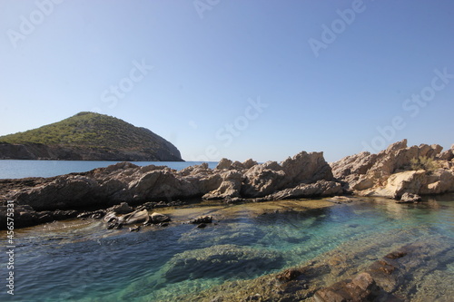 Rocks and rocky landscape visible in clear water.