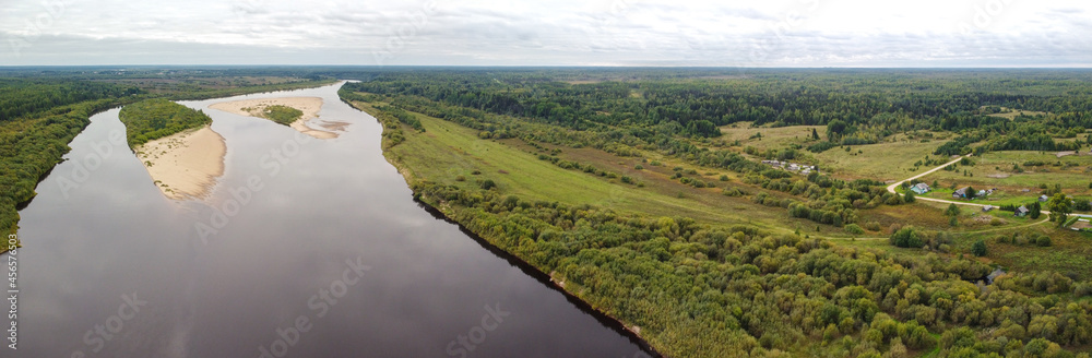 Aerial panorama of a wide river in a flat area with gentle banks and sandy islands. Vaga River, Arkhangelsk Region, Russia.