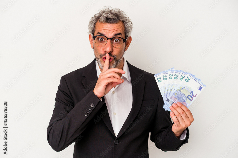 Middle age business man holding bills isolated on blue background keeping a secret or asking for silence. Middle age business man holding bills isolated on blue background keeping a secret or asking for silence.