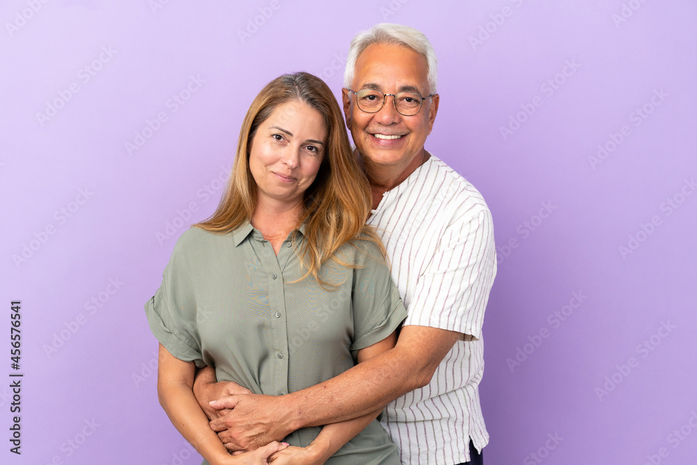 Middle age couple isolated on purple background hugging Middle age couple isolated on purple background hugging