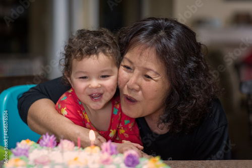 Grandmother and granddaughter blowing out candle on cake together