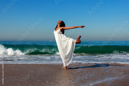 Tablou pe pânză Young female dancer poised on one leg in ocean waves
