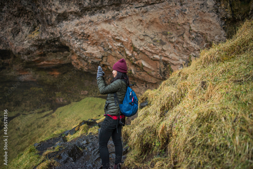 Fototapeta premium Female tourist photographing at Seljalandsfoss waterfall, Iceland