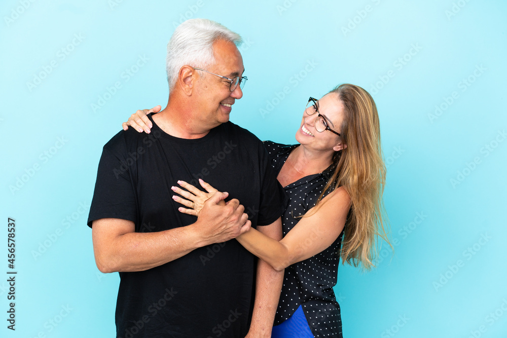 Middle age couple isolated on blue background laughing and hugging Middle age couple isolated on blue background laughing and hugging