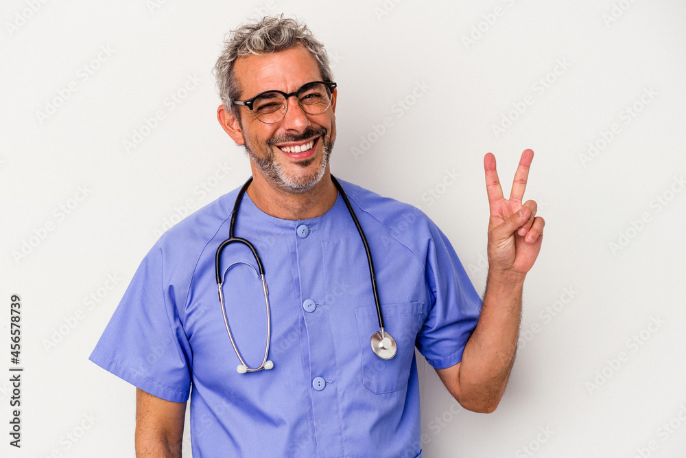 Middle age nurse caucasian man isolated on white background joyful and carefree showing a peace symbol with fingers. Middle age nurse caucasian man isolated on white background joyful and carefree showing a peace symbol with fingers.