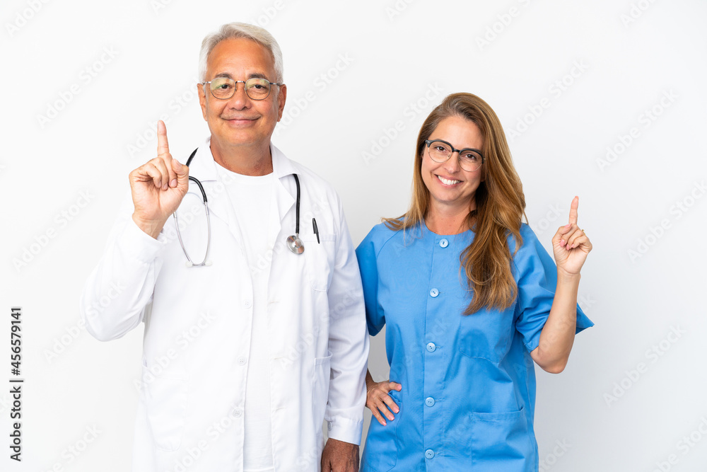 Middle age doctor and nurse isolated on white background showing and lifting a finger in sign of the best Middle age doctor and nurse isolated on white background showing and lifting a finger in sign of the best